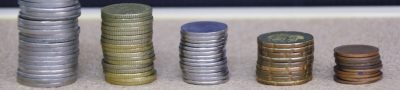 Stacks of coins arranged in ascending order on a wooden surface