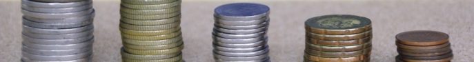 Stacks of coins arranged in ascending order on a wooden surface