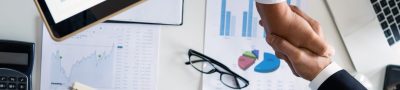 Business professionals handshake over graphs and charts in a corporate setting, symbolizing successful negotiation and agreem